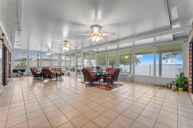 sunroom with a wall mounted AC, a water view, and ceiling fan