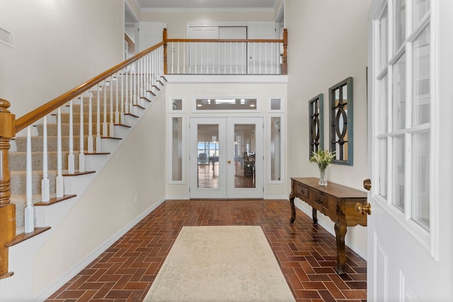 foyer with french doors, crown molding, and a high ceiling