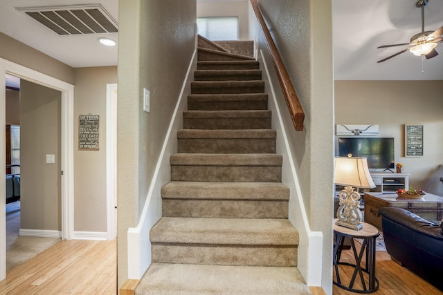 staircase with hardwood / wood-style flooring and ceiling fan