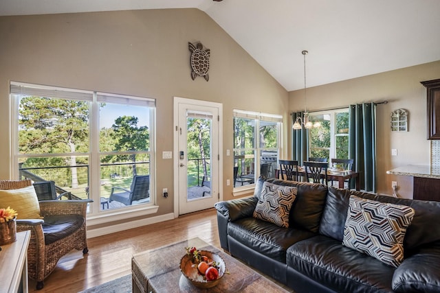 living room with light hardwood / wood-style flooring, high vaulted ceiling, and an inviting chandelier