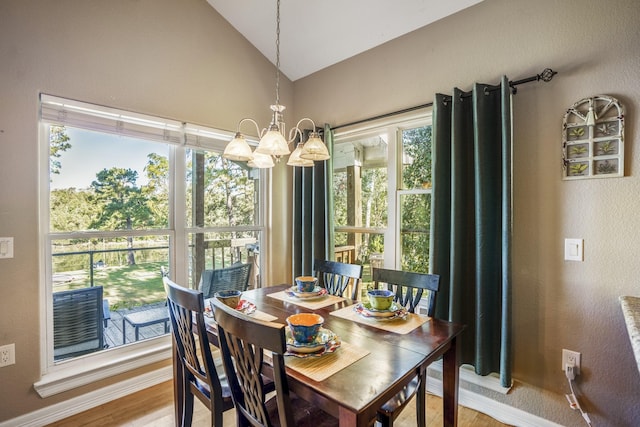 dining room with hardwood / wood-style floors, vaulted ceiling, and a notable chandelier