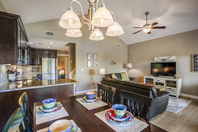 dining area with ceiling fan, dark hardwood / wood-style flooring, and vaulted ceiling