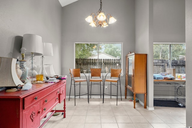 dining room with a notable chandelier, light tile patterned floors, and high vaulted ceiling