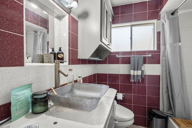 bathroom with curtained shower, tile walls, vanity, and toilet