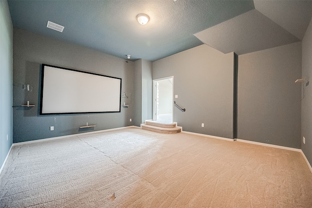 carpeted home theater with a textured ceiling and lofted ceiling