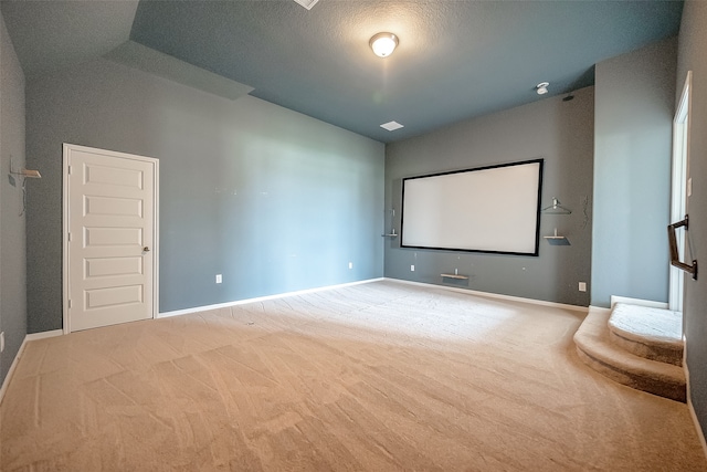 carpeted home theater room with lofted ceiling and a textured ceiling