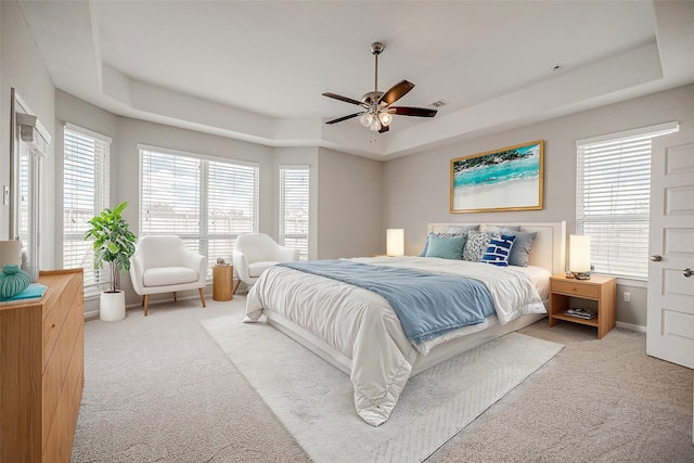 bedroom featuring multiple windows, light colored carpet, ceiling fan, and a raised ceiling