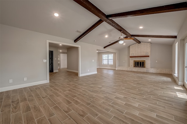 unfurnished living room with vaulted ceiling with beams, a brick fireplace, light hardwood / wood-style floors, and ceiling fan