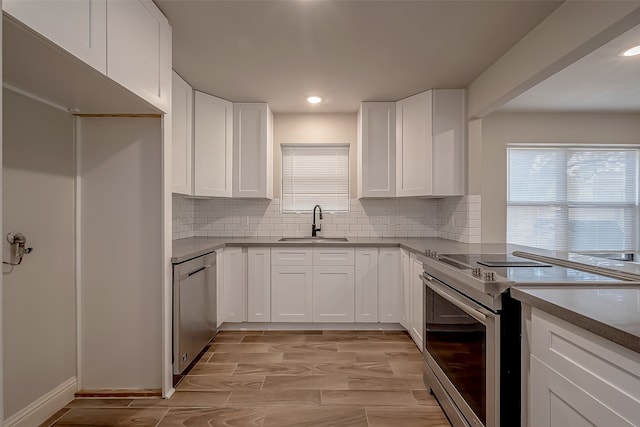 kitchen featuring appliances with stainless steel finishes, white cabinetry, sink, and tasteful backsplash