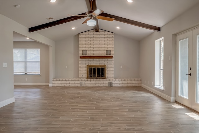 unfurnished living room featuring light wood-type flooring, vaulted ceiling with beams, a fireplace, and ceiling fan