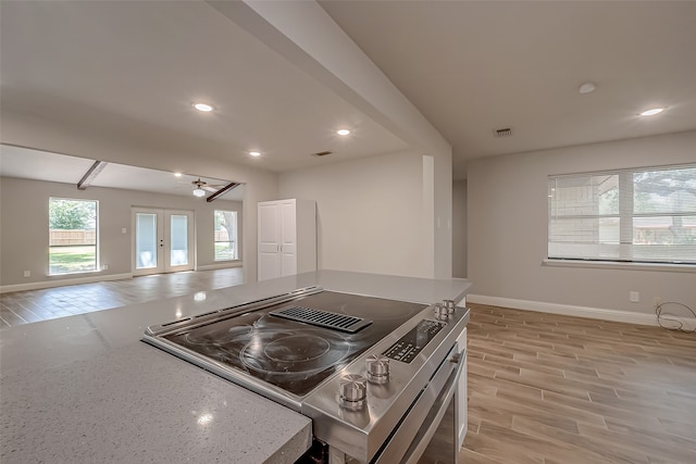 kitchen featuring stainless steel range with electric cooktop, french doors, light stone counters, and light hardwood / wood-style floors