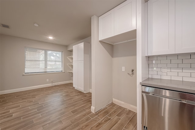 kitchen with decorative backsplash, light wood-type flooring, white cabinetry, and stainless steel fridge