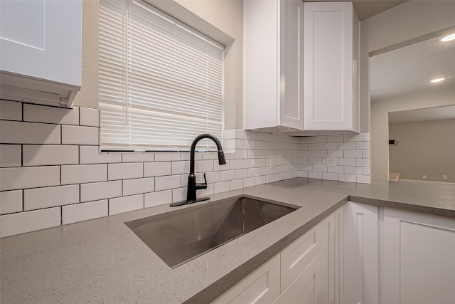 kitchen featuring white cabinetry, sink, and tasteful backsplash