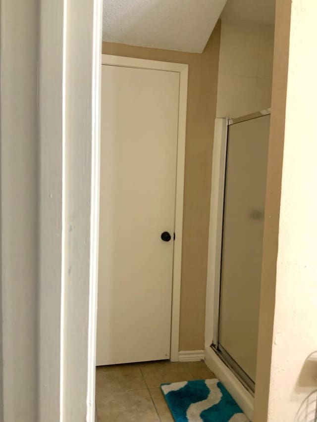 bathroom featuring a textured ceiling, a shower with shower door, and tile patterned floors