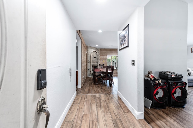 corridor with brick wall and hardwood / wood-style flooring