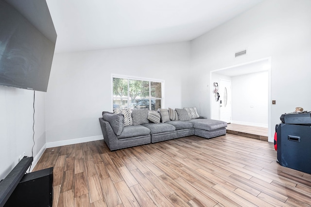 living room featuring high vaulted ceiling and light wood-type flooring