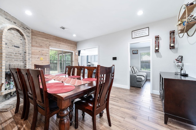 dining area with a fireplace, wood walls, and light hardwood / wood-style floors