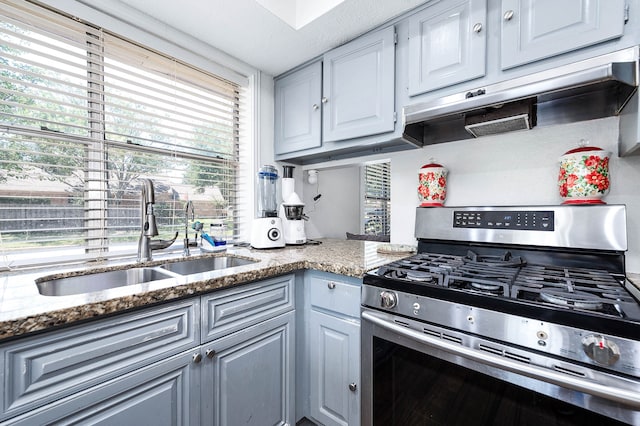 kitchen with stone countertops, sink, stainless steel range with gas cooktop, and gray cabinets