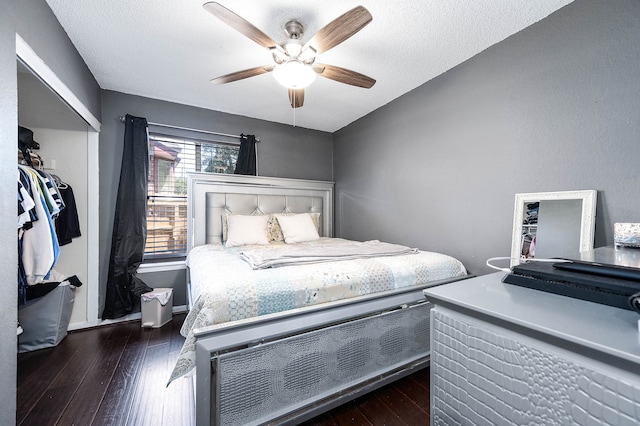 bedroom with ceiling fan, a textured ceiling, a closet, and dark hardwood / wood-style flooring