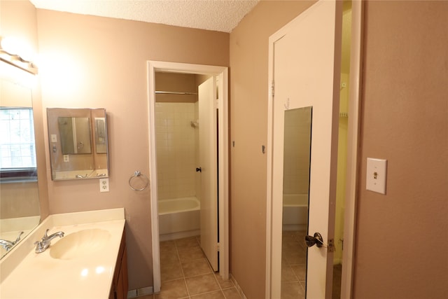 bathroom with a textured ceiling, tile patterned flooring, vanity, and tiled shower / bath