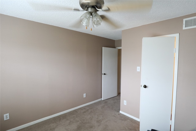 empty room featuring ceiling fan, a textured ceiling, and light carpet