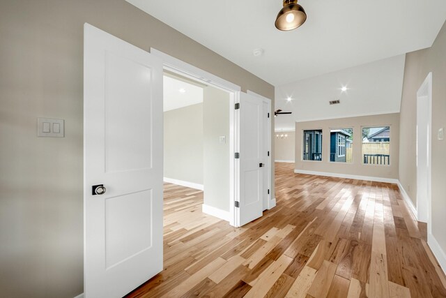 hall with light wood-type flooring and vaulted ceiling