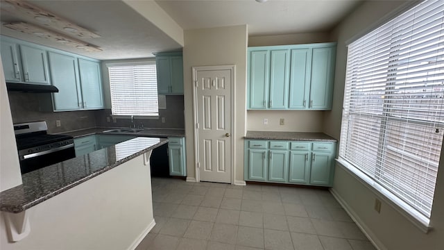 kitchen with a wealth of natural light, electric stove, dark stone countertops, and sink