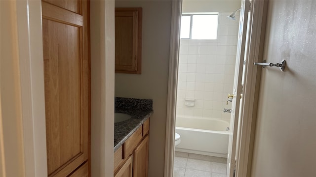 full bathroom with tile patterned flooring, tiled shower / bath, vanity, and toilet