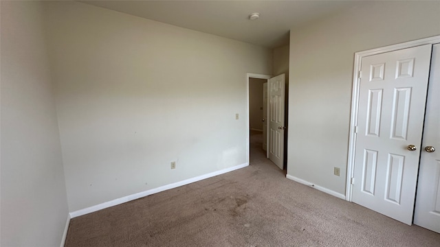 unfurnished bedroom with light colored carpet and a closet