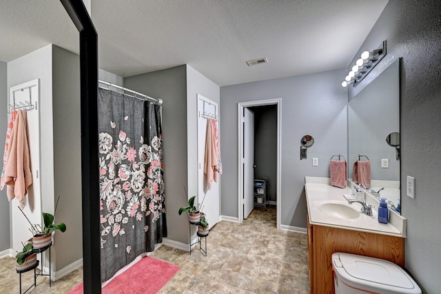 bathroom featuring a textured ceiling, vanity, and toilet