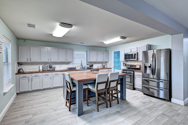 kitchen featuring light hardwood / wood-style flooring, appliances with stainless steel finishes, butcher block countertops, and plenty of natural light