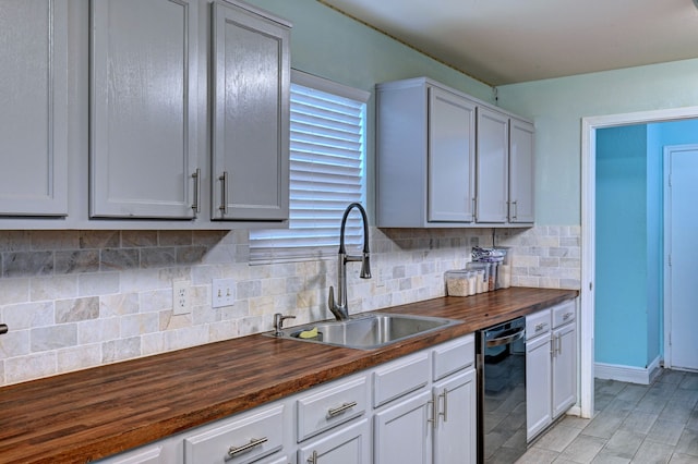 kitchen with black dishwasher, sink, tasteful backsplash, and wooden counters