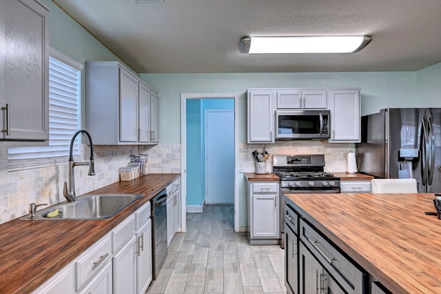 kitchen with decorative backsplash, black appliances, sink, and wooden counters