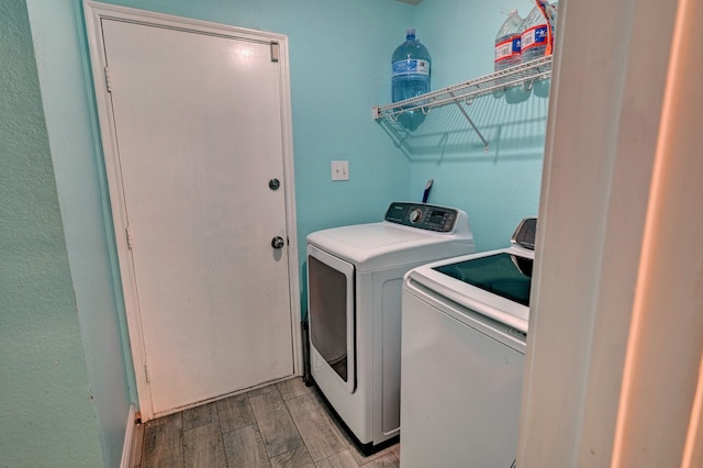 clothes washing area featuring light hardwood / wood-style floors and washing machine and dryer