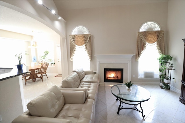 living area featuring a high end fireplace, plenty of natural light, a towering ceiling, and light tile patterned floors