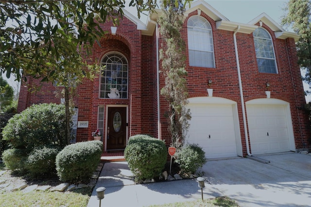 view of front of property featuring a garage, concrete driveway, and brick siding