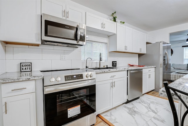 706 Beaumont St, Anahuac, TX 77514 - kitchen with appliances with stainless steel finishes, a sink, ceiling fan, white cabinetry, and tasteful backsplash