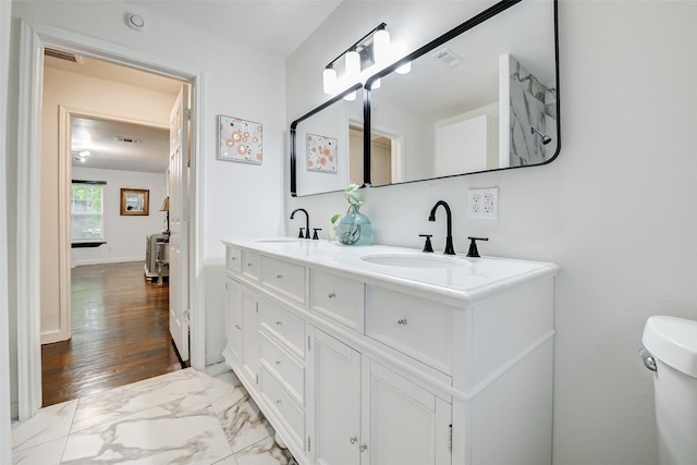 706 Beaumont St, Anahuac, TX 77514 - full bathroom featuring double vanity, toilet, and wood finished floors
