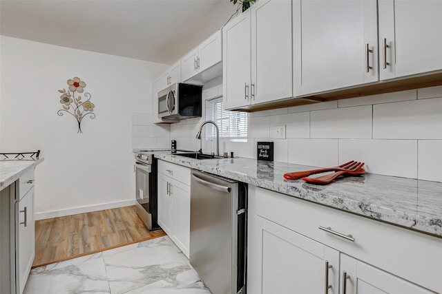 706 Beaumont St, Anahuac, TX 77514 - kitchen featuring stainless steel appliances, light marble finish floors, backsplash, light stone counters, and white cabinetry