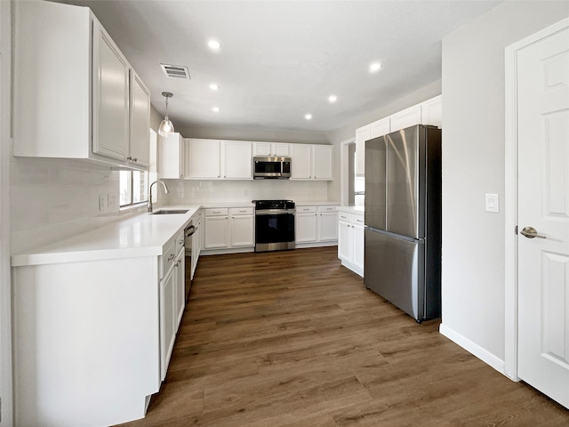 kitchen featuring sink, hanging light fixtures, backsplash, white cabinets, and appliances with stainless steel finishes