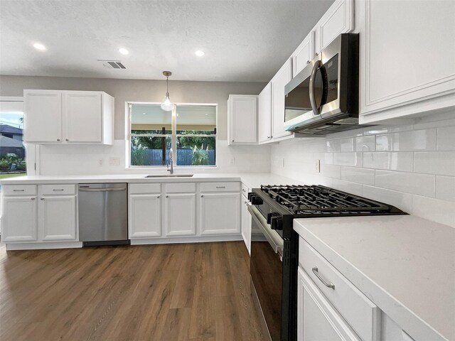 kitchen featuring hanging light fixtures, white cabinets, and stainless steel appliances