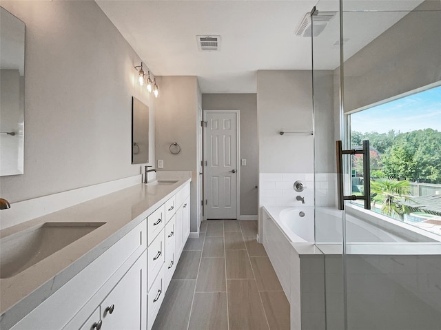 bathroom featuring a relaxing tiled tub and vanity