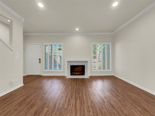 unfurnished living room featuring ornamental molding, a wealth of natural light, a fireplace, and hardwood / wood-style floors