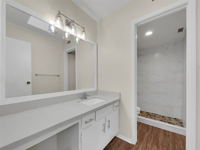 bathroom with vanity, hardwood / wood-style floors, toilet, and tiled shower