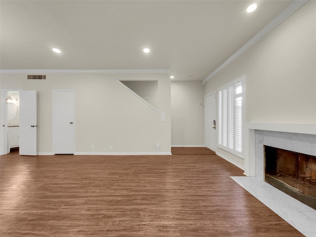 unfurnished living room with wood-type flooring, crown molding, and a premium fireplace