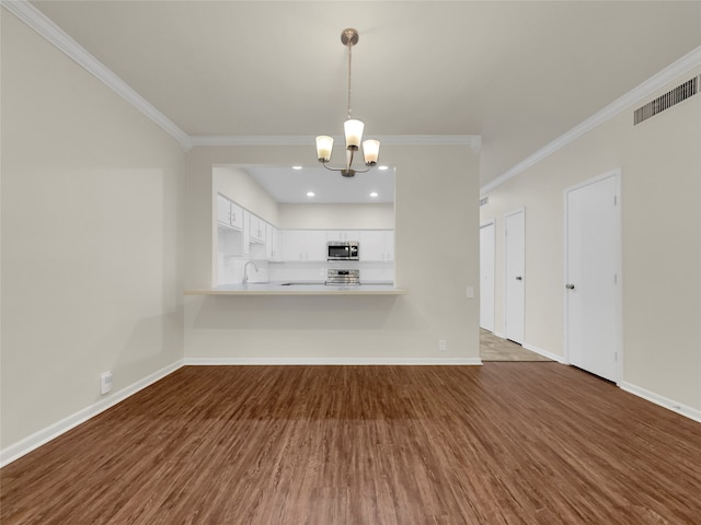 unfurnished living room with an inviting chandelier, sink, dark hardwood / wood-style floors, and crown molding