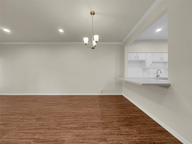 unfurnished dining area with ornamental molding, sink, a chandelier, and dark hardwood / wood-style flooring