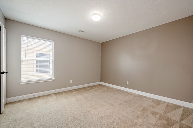 spare room featuring a textured ceiling and light carpet