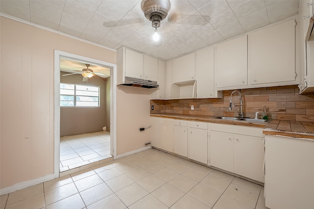 kitchen featuring decorative backsplash, light tile patterned flooring, white cabinets, ceiling fan, and sink