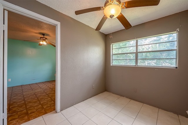 unfurnished room with a wealth of natural light, ceiling fan, light tile patterned floors, and a textured ceiling